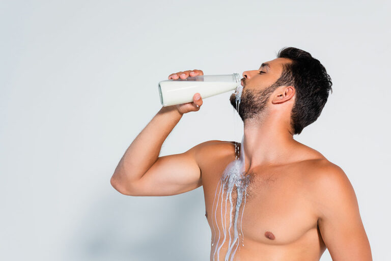 Muskulöser Mann trinkt frische Milch aus der Flasche