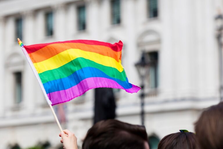 LGBTQ Fahne wird in einer Stadt hochgehalten